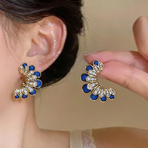 Macro detail shot of vintage blue floral stud earrings with sparkling white crystal accents