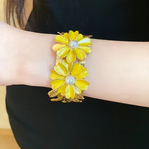 Close-up shot of an elegant yellow enamel flower bracelet with pearls worn on a wrist