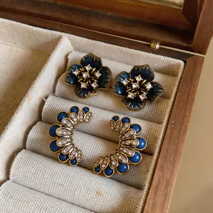 Detail shot of vintage dark blue floral studs and crystal fan earrings in a jewelry box