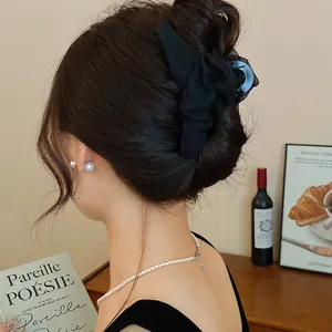 Detailansicht einer eleganten Haarklammer aus schwarzem Netzstoff an einem Modell.
