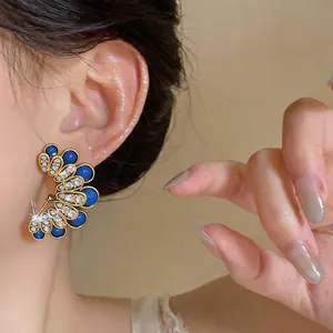 Close-up of elegant flower stud earrings featuring blue gems and sparkling crystals