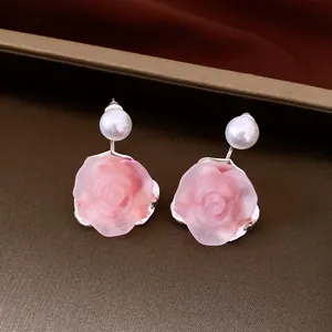 Close-up of pink resin rose earrings featuring elegant white pearl studs and silver setting