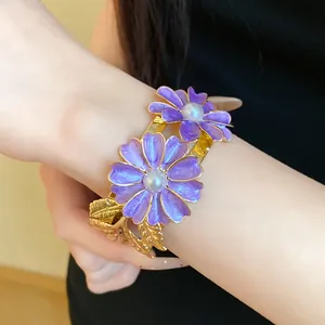 Detail showing a double-layered open bangle with purple enamel flowers and pearls