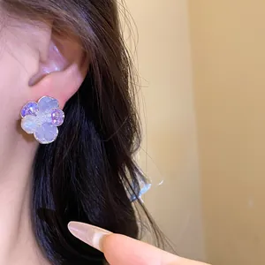 Close-up detail of an elegant flower stud earring with purple zircon and white pearl