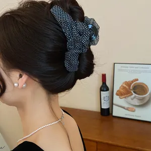 Detailansicht einer schwarzen Haarklammer mit Polka Dots auf einem eleganten Haarknoten