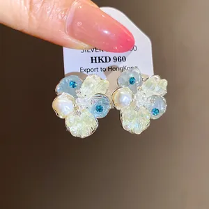 Detailed close-up view of zircon and pearl flower stud earrings with blue accents