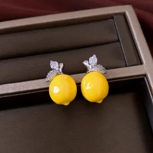 Close-up detail of luxury yellow lemon shaped earrings with sparkling zircon encrusted leaves