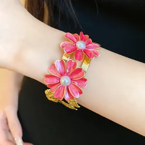 Exquisite close-up of a gold cuff bracelet featuring vibrant pink enamel flowers and pearls