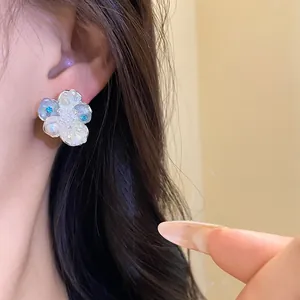 Close-up detail of an exquisite zircon and pearl flower stud earring worn on the ear.