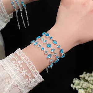 Detailed view of elegant blue crystal teardrop bracelets worn on wrist with lace sleeve