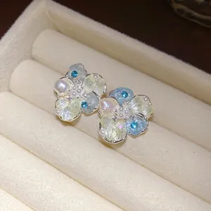 Close-up view of exquisite floral stud earrings with pearls inside a velvet jewelry box.