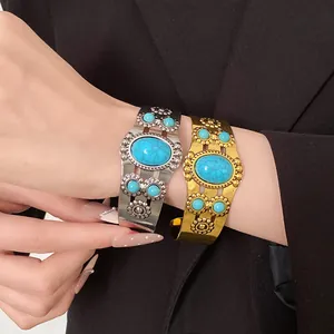 Detailed view of vintage turquoise open cuff bracelets with floral metal engraving on model's wrist