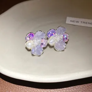 Detailed close-up of vintage dainty flower stud earrings with purple crystals and pearls