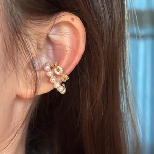 Close-up of elegant C-shape ear cuff with pearls and cubic zirconia on model ear