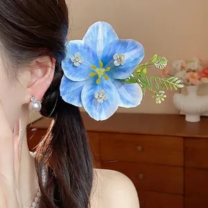 Elegant blue fabric flower hair clip with rhinestones worn by model in a side view