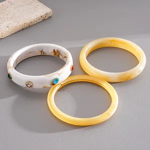 Vista dettagliata di tre bracciali in resina con motivi marmorei e decori in strass