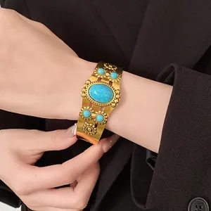 Detail view of vintage gold-tone cuff bracelet with turquoise stones and floral patterns.