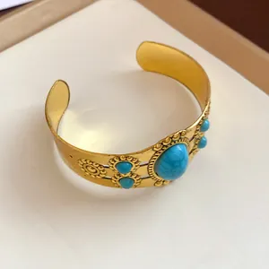 Close-up view of a vintage gold-tone cuff bracelet featuring oval turquoise stones
