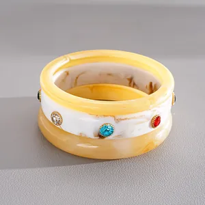 Dettaglio di un set di 3 bracciali in resina marmorizzata con vivaci strass colorati