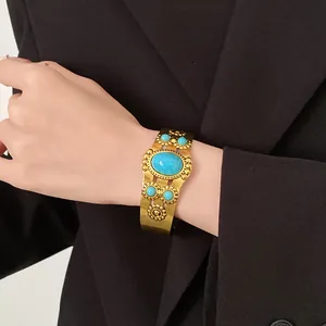 Detailed view of a vintage gold-toned open cuff bracelet featuring turquoise stones