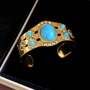 Close-up of vintage gold cuff bracelet with oval turquoise stone and flower accents