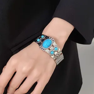 Close-up of a vintage-style silver cuff bracelet with turquoise-like stones on a hand