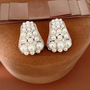 Detailed view of vintage clustered pearl earrings with sparkling zircon accents on a velvet box.