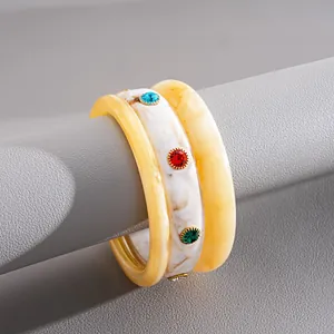 Dettaglio ravvicinato di set bracciali in resina marmorizzata con strass colorati