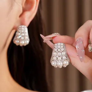 Close-up of elegant silver needle stud earrings with multiple pearls and sparkling zircons
