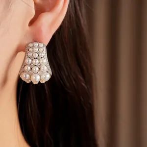 Close-up of elegant vintage-style earrings with layered white pearls and zircons.