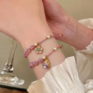Hand-woven pink beaded bracelet set with flower and pearl charms on wrist
