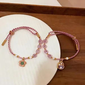 Elegant hand-woven braided bracelets featuring pearl and floral pendants displayed on white plate