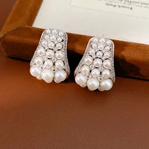 Detail view of vintage pearl stud earrings with sparkling zircon accents on leather.