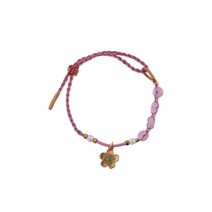Handmade pink woven rope bracelet featuring pearls and a delicate pink flower pendant charm