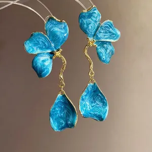 Vintage blue enamel flower dangle earrings with gold-tone stems on neutral background.