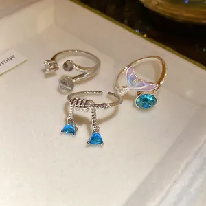 Détail de trois bagues en argent avec des zircons et des pierres bleues