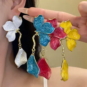 Close-up of retro flower drop earrings showing fine enamel texture and gold-tone details.