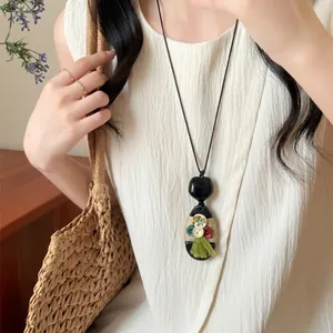 Ethnic bohemian long pendant necklace featuring black oval pendant with green tassel