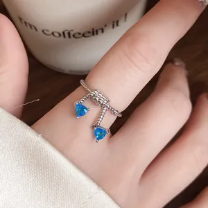 Gros plan sur une bague réglable argentée ornée de deux pendentifs en zircon bleu