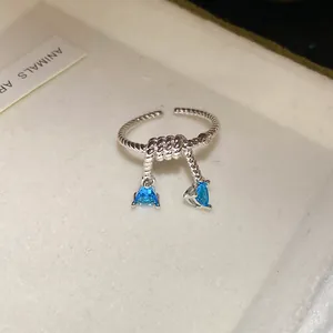 Détail d'une bague nœud en argent avec deux pendentifs en zircon bleu en forme de triangle