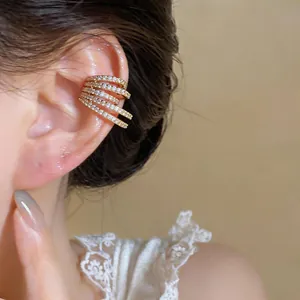 Close-up view of elegant multi-layered gold ear cuff with sparkling zircons on ear