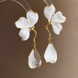 Detailed view of elegant white enamel flower petal dangle earrings with vintage gold edges