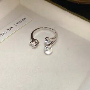 Gros plan d'une bague ouverte en argent minimaliste avec zircon et pierres claires