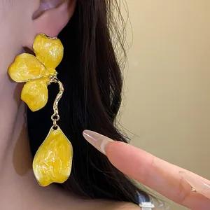 Macro view of elegant vintage yellow enamel flower drop earrings shown on model ear