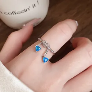 Vue détaillée d'une bague argentée avec deux zircons bleus triangulaires et nœud