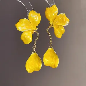 Detailed close-up of vintage yellow enamel flower drop earrings with golden trim