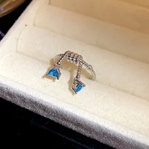 Détail d'une bague ajustable en argent avec deux élégants pendentifs en zircon bleu.