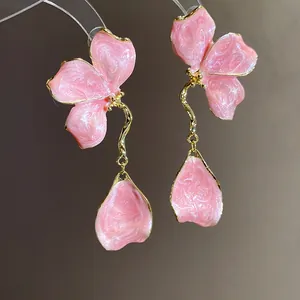 Detailed macro view of vintage pink enamel flower drop earrings with elegant golden stems