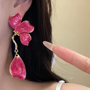 Detailed view of vintage style pink enamel flower dangle earrings with gold-tone accents