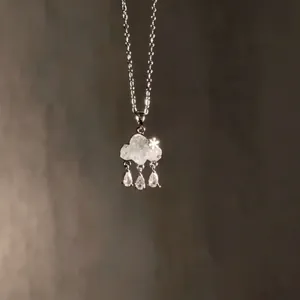Detailed close-up of a light blue cloud pendant necklace with dangling raindrop zircon stones